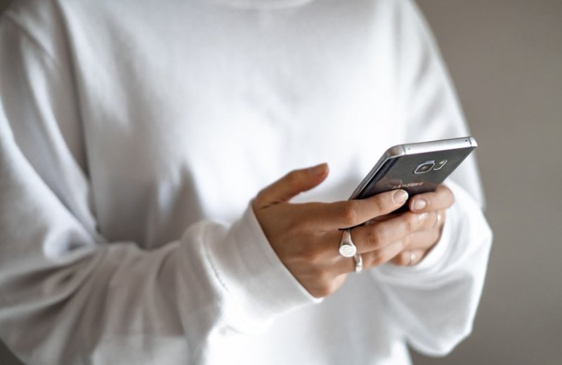 Hand holding a smartphone, a quick check-in from afar