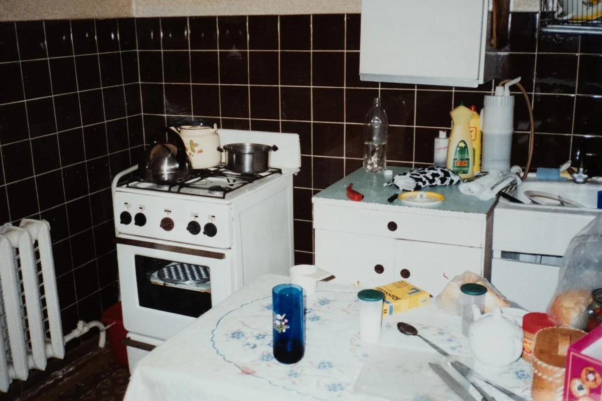 Inside a working-class Russian apartment kitchen with brown tile and a gas range