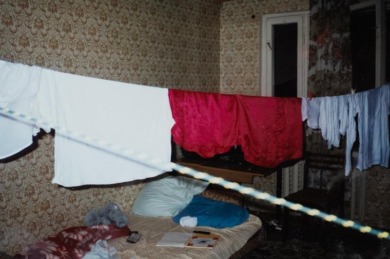 Dim Soviet-era bedroom with clothes strung on a line on a dark evening