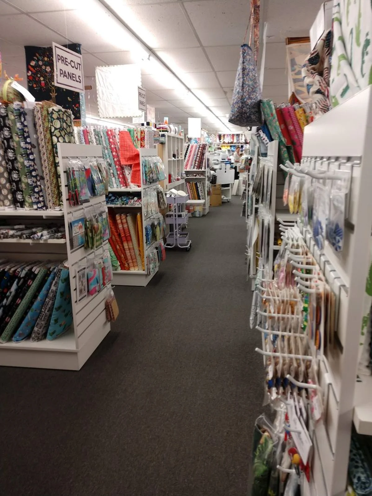 Interior view of a fabric store aisle with colorful textile shelves