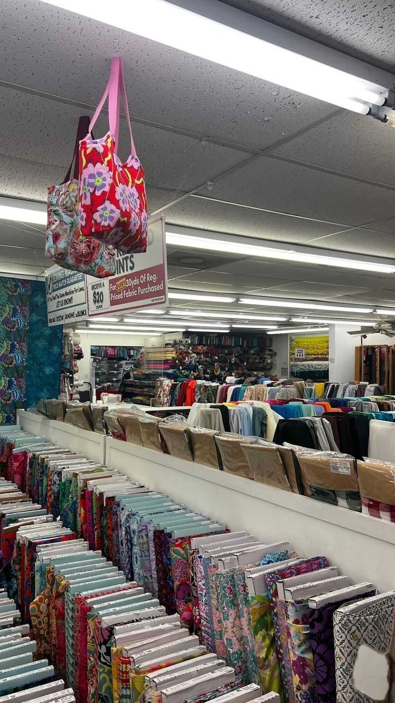 Fabric store interior with colorful bolts and hanging floral tote bags