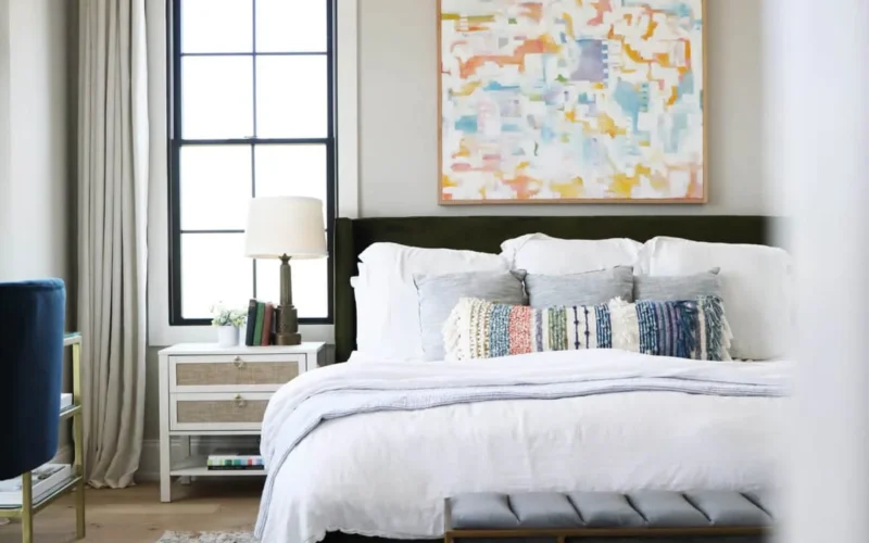 Modern bedroom with white bed, abstract art, and patterned rug