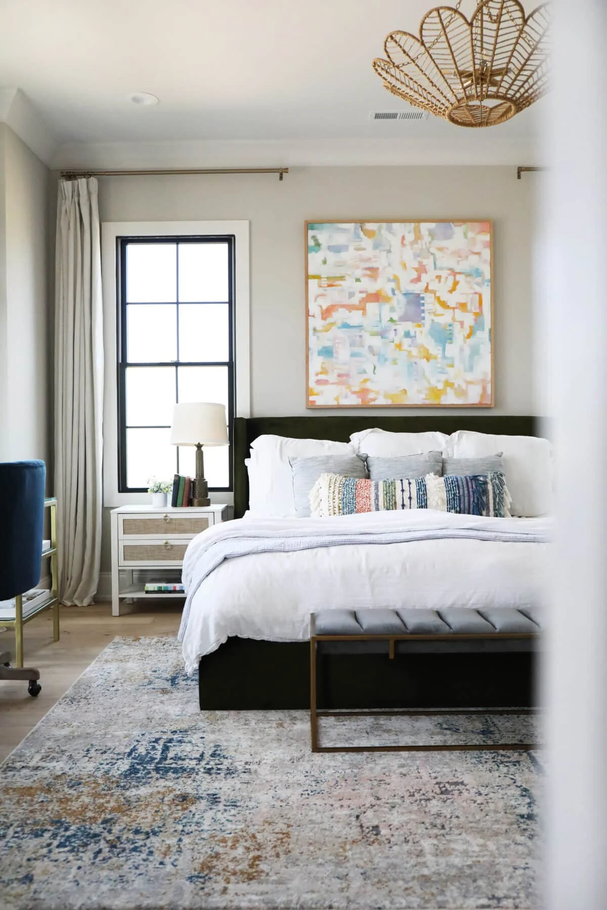 Modern bedroom with white bed, abstract art, and patterned rug