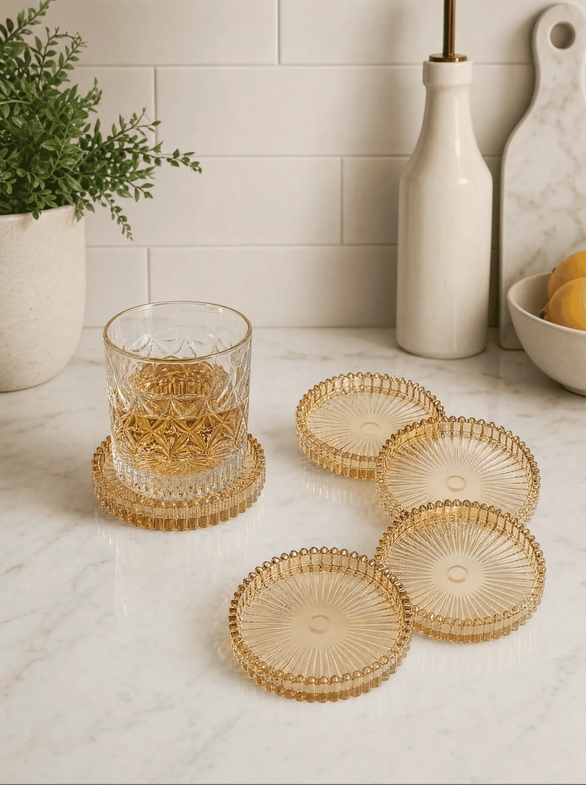 Amber glass coasters on a marble kitchen counter with a crystal tumbler
